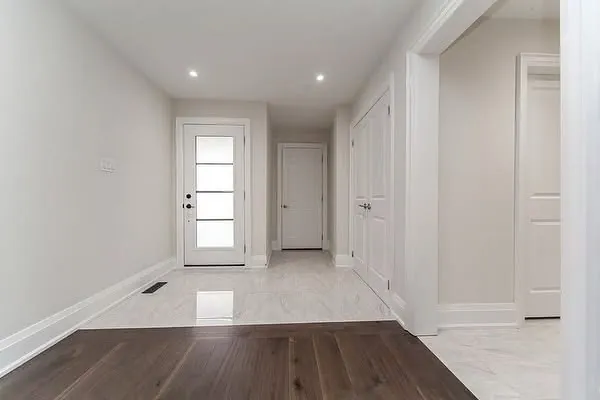 A bright front hall with marble-look tile and a glass-panel front door.