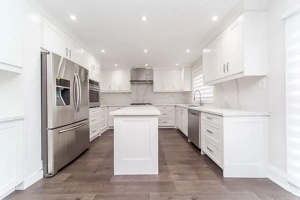 A white kitchen with an island and stainless appliances.