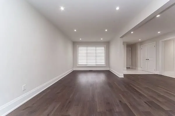 A long open-concept main floor with dark hardwood and pot lights.