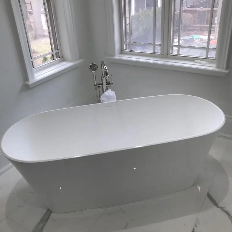 A white freestanding tub under a bay window with a floor-mounted faucet.