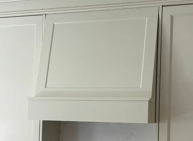 The same spot with a finished, painted range hood cover matching the cabinets.